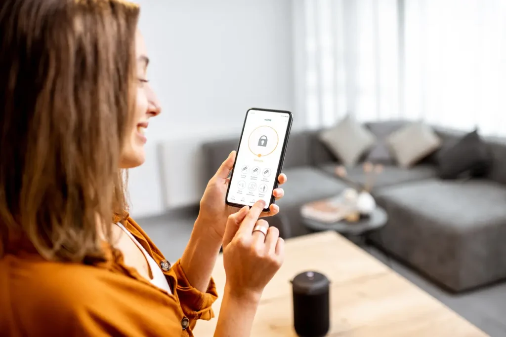 Câmeras e alarmes de segurança: como combinar para a máxima proteção 2 Mulher olhando as Câmeras e alarmes de segurança EMIVE pelo celular